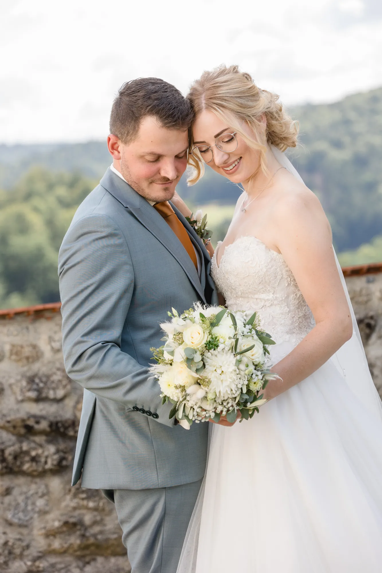 Brautpaar mit Brautstrauß vor weiter Landschaft – Hochzeitsfotograf aus Niederbayern